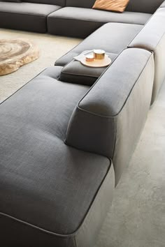 a large gray couch sitting on top of a white floor next to a wooden table