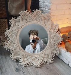 a woman taking a photo with her camera in front of a lace doily mirror