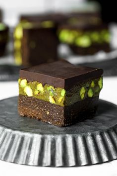 chocolate and pistachio dessert sitting on top of a metal plate