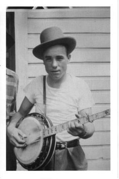 an old photo of a young man holding a guitar