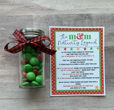 a jar filled with green and red candies next to a christmas card on a wooden table