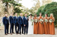 a group of people standing next to each other in front of some bushes and trees