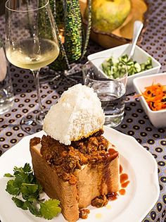 a white plate topped with food next to glasses of wine and bowls filled with vegetables