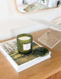 a candle sitting on top of a book next to a mirror