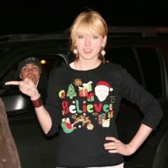 a woman standing in front of a car with her hand on her hip and pointing to the side