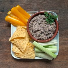 a plate with celery, carrots and crackers on it next to chips