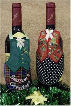 two wine bottles decorated with different designs and colors, sitting in the grass next to each other