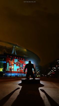 a skateboarder is riding his board on the sidewalk in front of a stadium