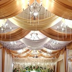 an elaborately decorated banquet hall with chandeliers and draped drapes on the ceiling