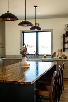 a large kitchen with an island in the middle and two pendant lights hanging from the ceiling