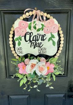 a floral wreath hanging on the front door of a house that says, claire mae