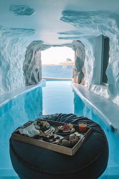 an indoor swimming pool with ice formations and food on the tray in the middle, surrounded by blue water