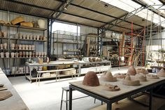 a room filled with lots of pottery on top of wooden tables next to each other