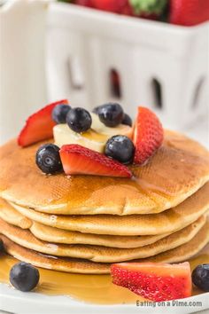 a stack of pancakes topped with fruit and syrup