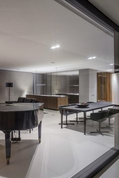 a large piano is in the middle of a room with glass walls and floor to ceiling windows