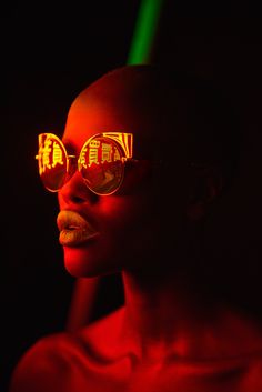 a woman wearing sunglasses with red light reflecting on her face