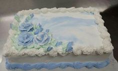 a blue and white frosted cake with flowers on it