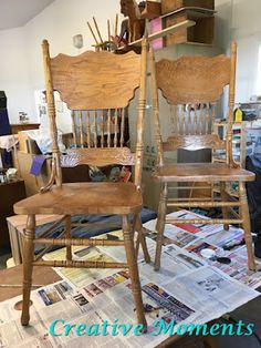 two wooden chairs sitting next to each other on top of a pile of paper and magazines