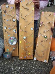 two children are playing with wooden pegs and beaded boards on the ground while another child is sitting next to them