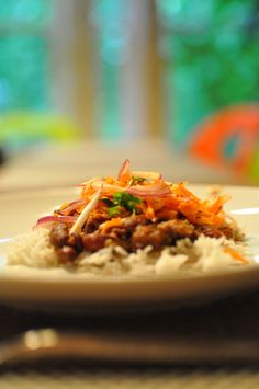 a white plate topped with rice covered in meat and veggies next to a fork