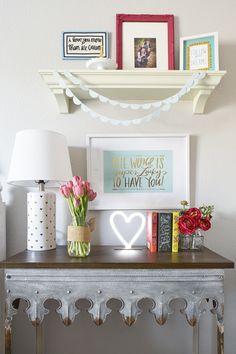 a table with flowers, books and pictures on top of it next to a lamp