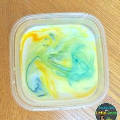 a plastic container filled with liquid sitting on top of a wooden table next to a green and yellow substance