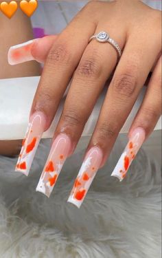 a woman's nails with orange and white designs on them