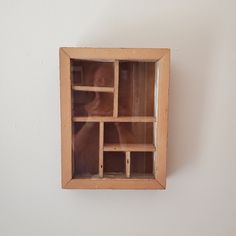 a wooden shelf with several compartments in it on the wall next to a white wall