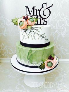 a green and white wedding cake with flowers on top