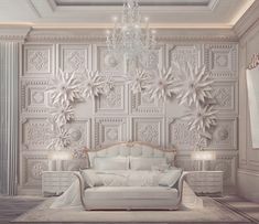 a white couch sitting under a chandelier next to a wall covered in snowflakes