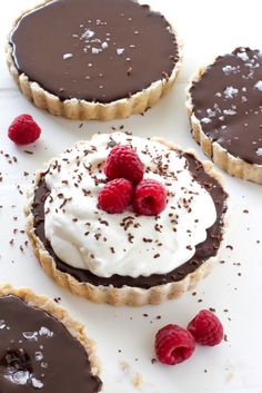 chocolate tarts topped with whipped cream and raspberries