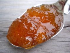 a spoon filled with jelly on top of a wooden table