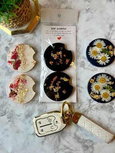 four flowered plates and a keychain on a marble table with a plant in the background