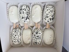 six white and black cake pops in a box