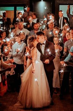 a bride and groom kissing in front of a crowd of people holding sparkler wands