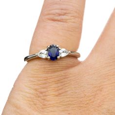 a woman's hand with a blue and white diamond ring on top of it