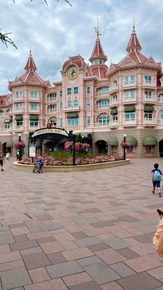 people are walking around in front of a pink building