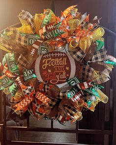 a wreath with football and fall leaves on it is hanging in front of a door