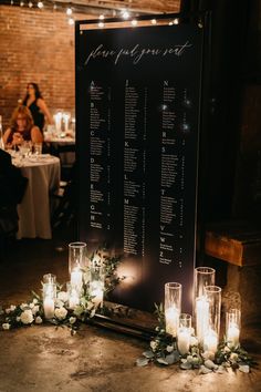 a table with candles and flowers on the floor next to a sign that says guest list