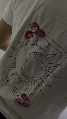 a person wearing a white t - shirt with red flowers on it