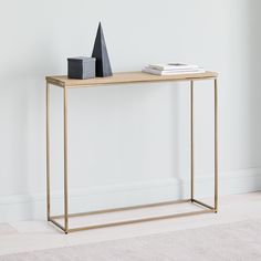 a wooden table with a black bag and some books on it next to a white wall