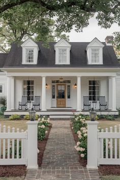 a white house with two front porches and three chairs on the front door is shown