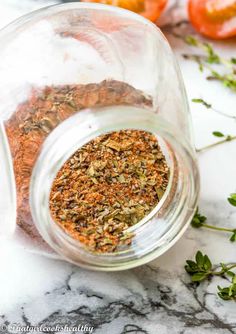 a jar filled with spices sitting on top of a counter next to tomatoes and herbs