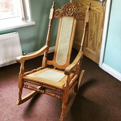 a wooden rocking chair sitting in a room next to a radiator and window