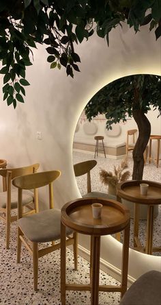 the interior of a restaurant with tables and chairs in front of a circular mirror on the wall