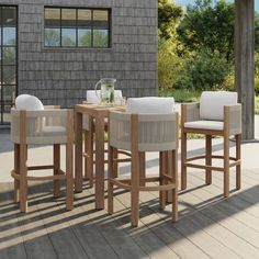 a wooden table with four chairs and a glass vase on top of it in front of a house