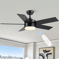 a black ceiling fan with remote control in a living room next to a large window