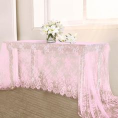 a pink table cloth with white flowers in a vase on the floor next to it