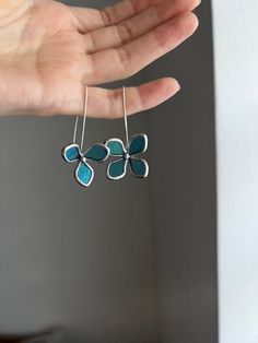 a person is holding some kind of earrings in their hand and it has blue flowers on it