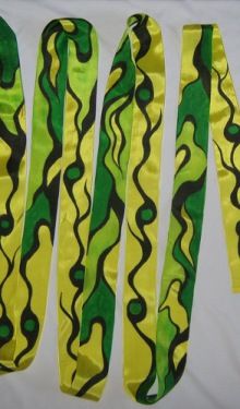 four pieces of yellow and green ribbon with black swirls